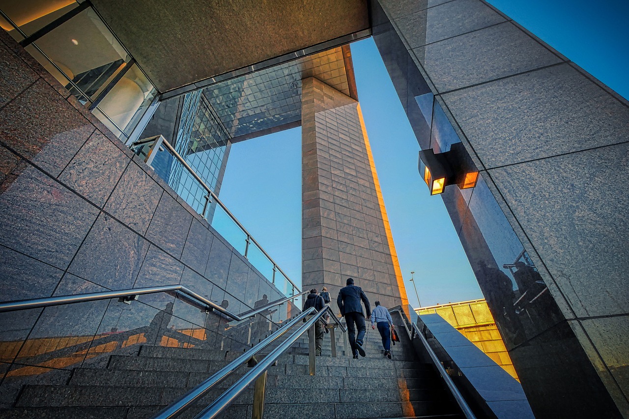 Two businessmen climb a sleek, modern high-rise staircase, symbolizing professional growth.