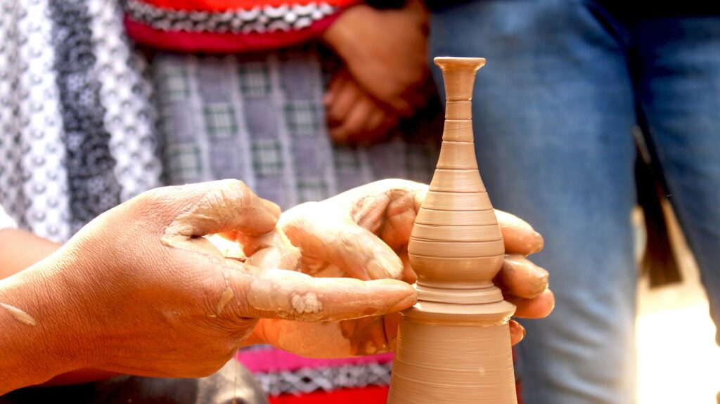 Close-up of artisan shaping a delicate clay vase with hands, showcasing skill and tradition.