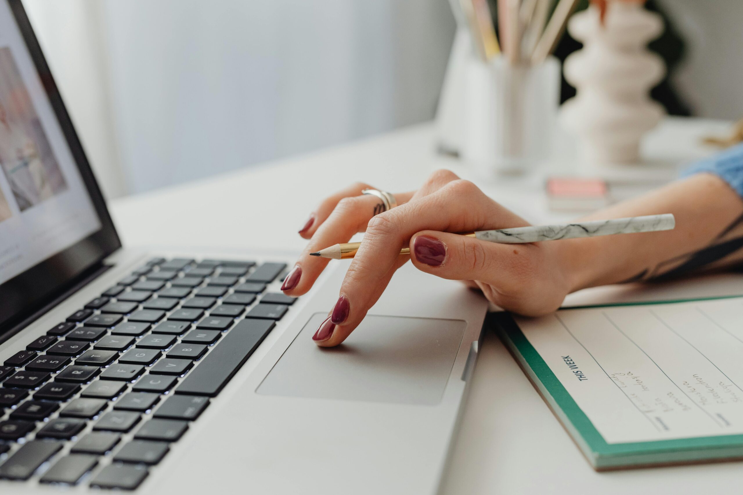 Person typing on laptop, notebook and pen nearby, crafting a post-interview email.