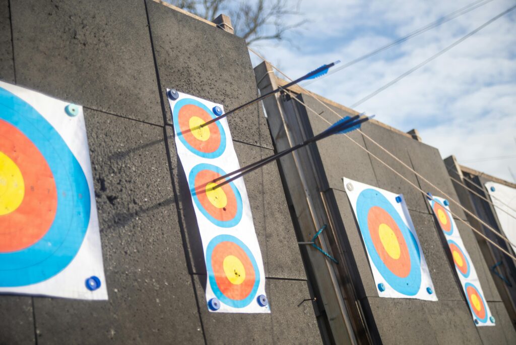 A detailed shot of arrows piercing through colorful archery targets on an outdoor range.