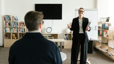 Businesswoman giving presentation in modern office with bookshelves and clock.