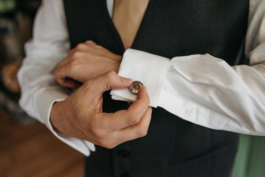 A detailed close-up of a person adjusting a cufflink on a white dress shirt, highlighting fashion elegance.