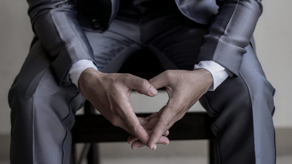 Close-up image of hands resting on lap in a classic business suit, conveying elegance and professionalism.